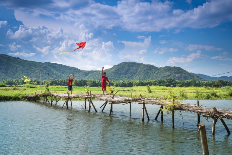 Children flying kite over makeshift bridge