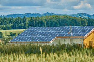 Rooftop solar panel array with fields and mountains.